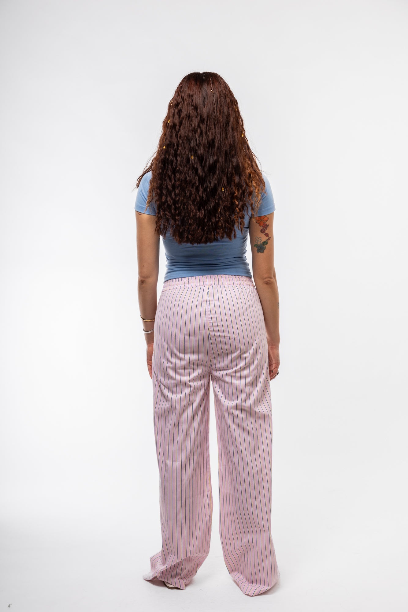 Back profile image view of lightweight pink stripe trousers for women with comfortable drape.