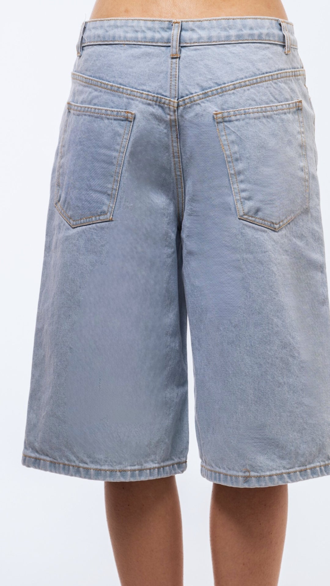 Back view of longline denim jorts featuring patch pockets and a clean yoke seam.