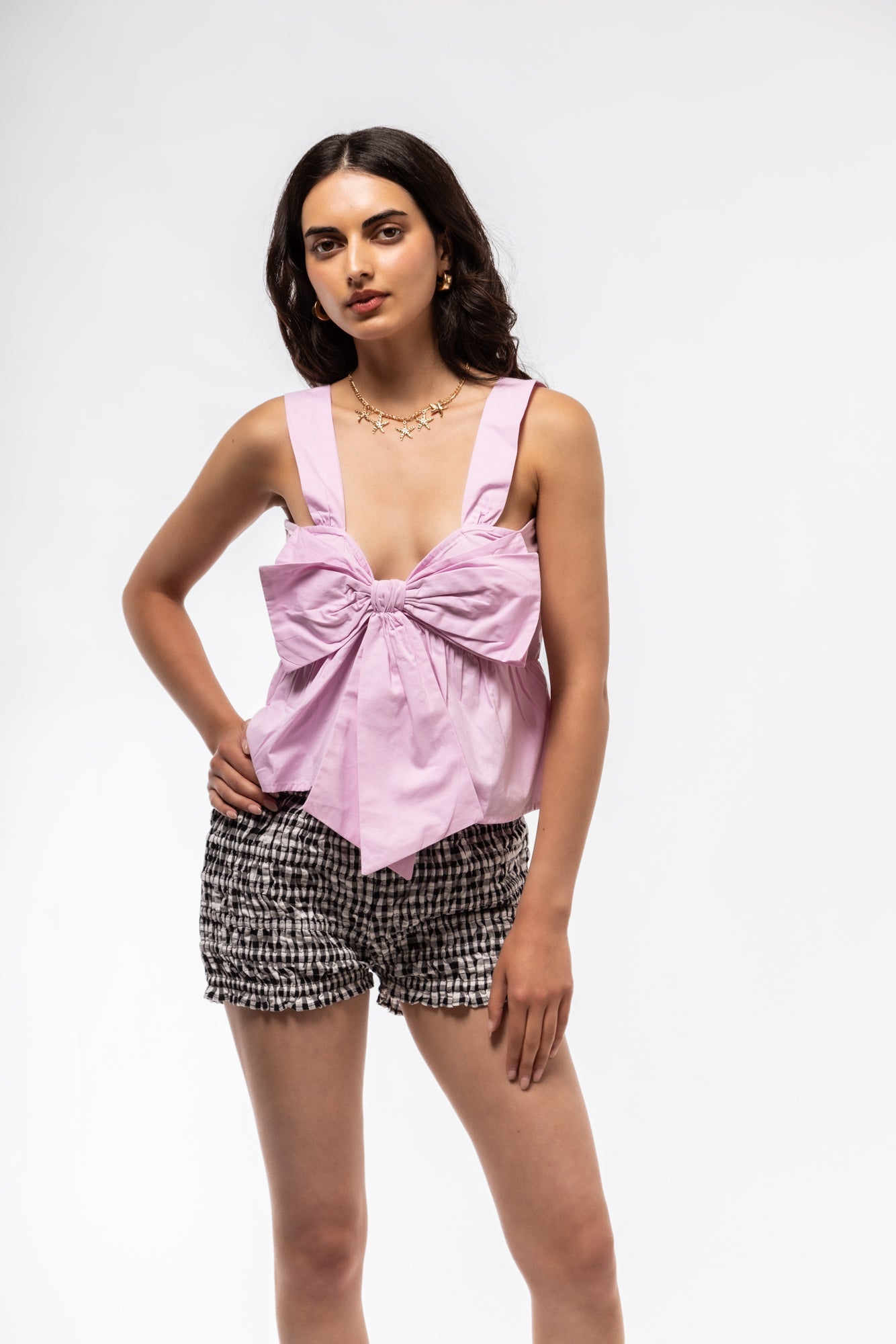 Front view of women’s pink cami top with bow detail and thin adjustable straps.