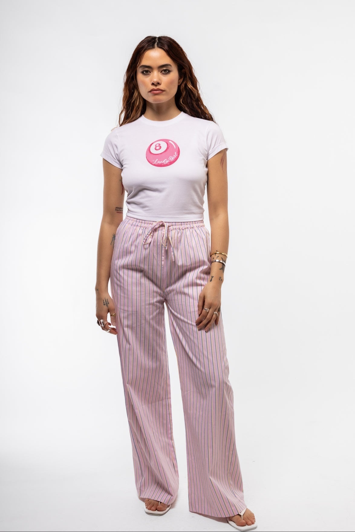 Pastel pink striped trousers for women with wide leg and front drawstring, ideal for lounging or travel.