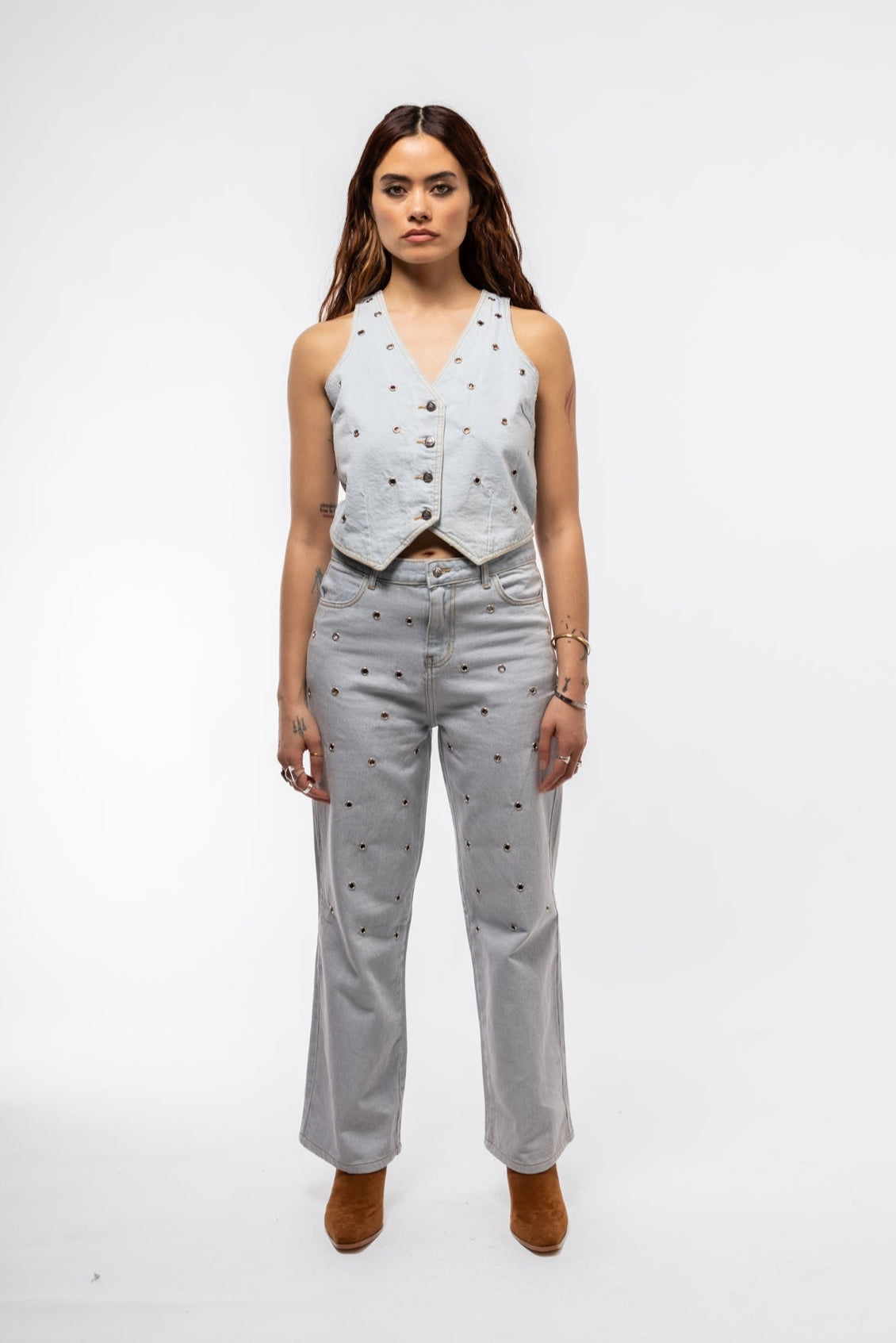 Model wearing stud denim waistcoat styled open over a tank for a layered edgy look