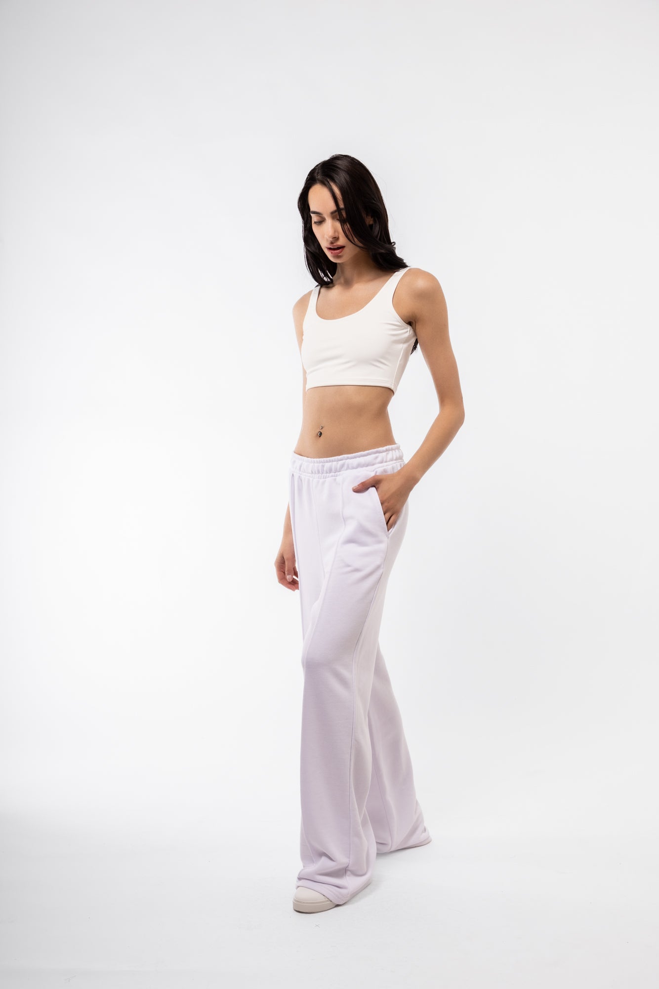 Woman wearing a white crop top and wide-leg pants on a white background