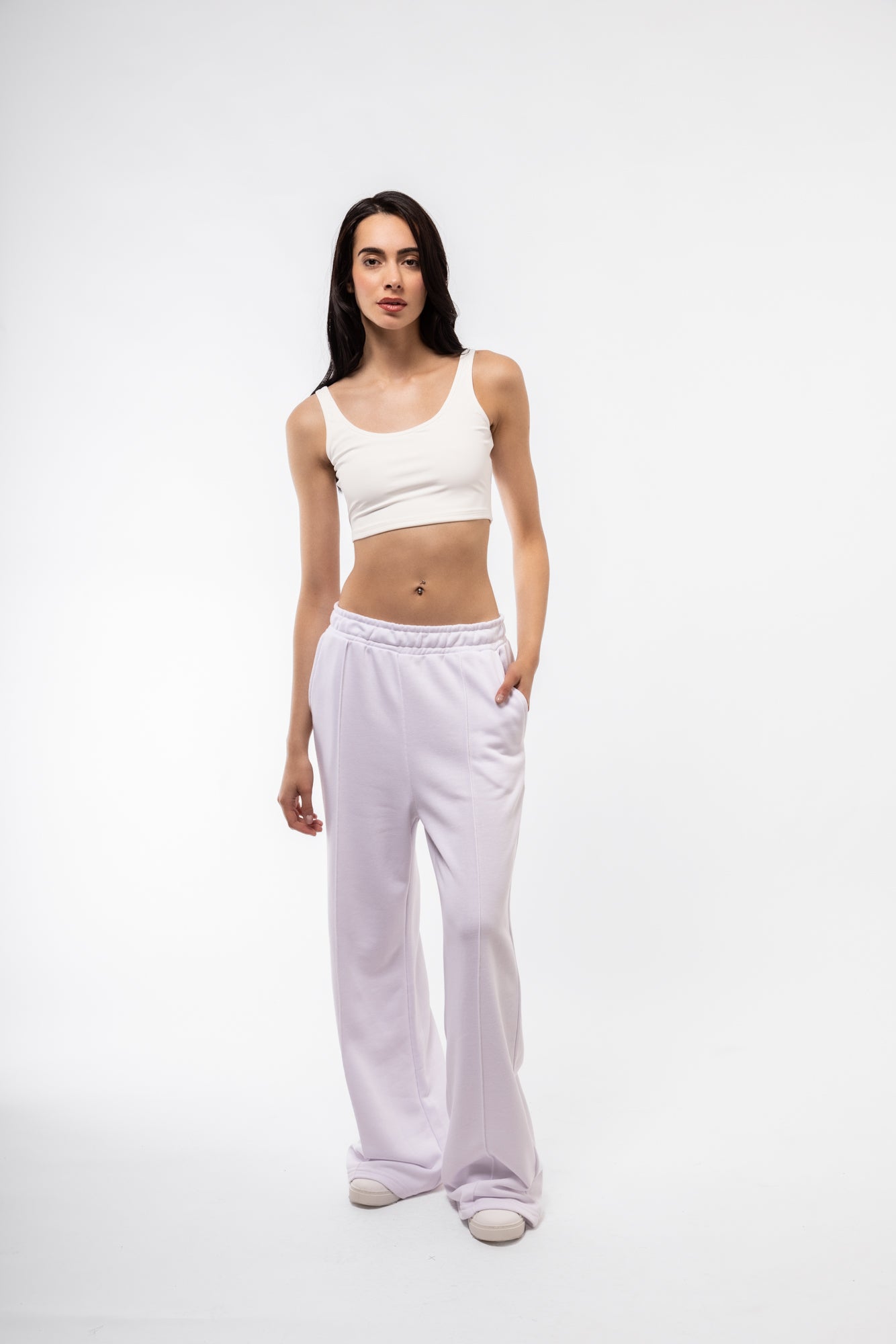 Woman wearing a white tank top and pants on a white background