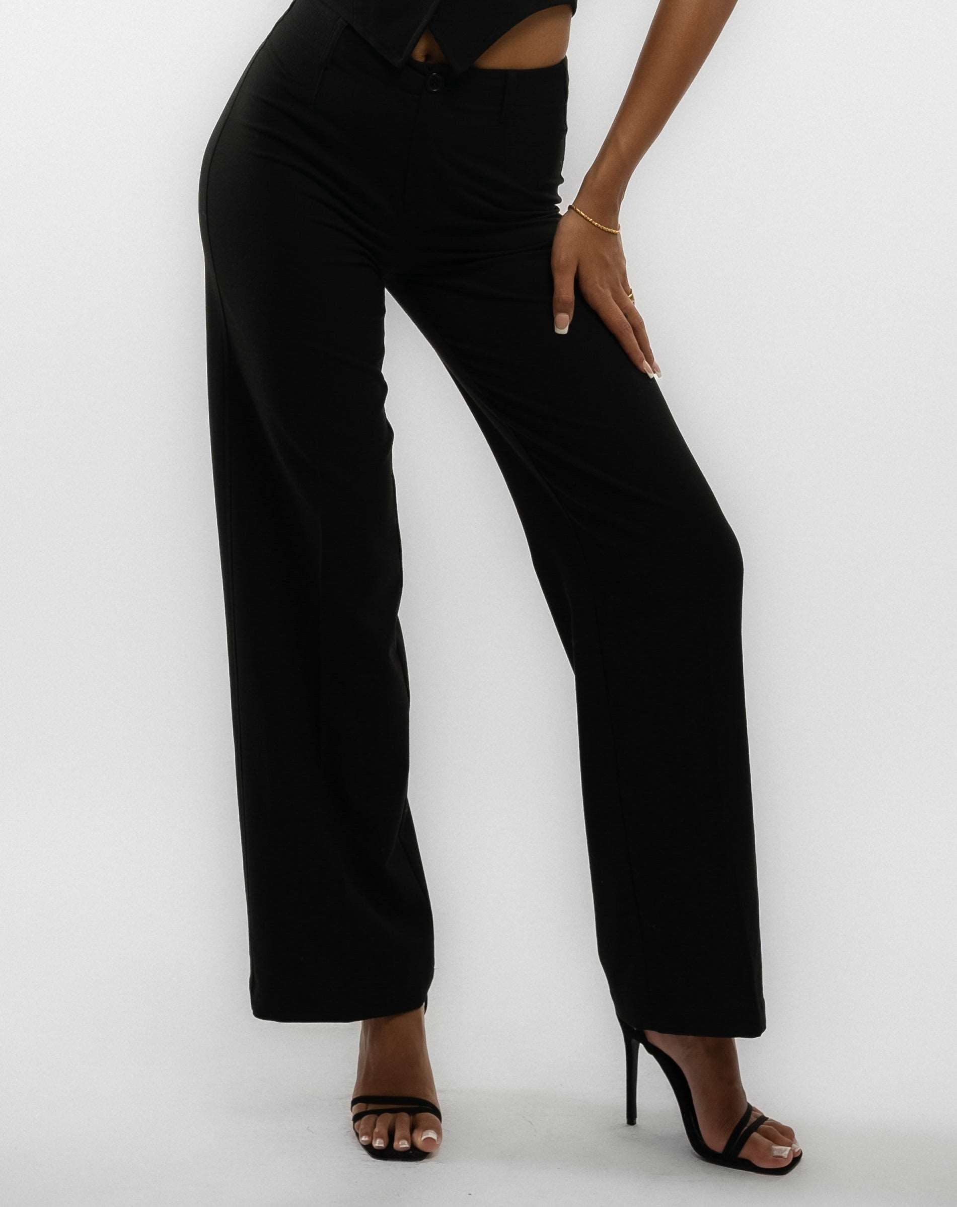 a woman in a black tailored wide leg trouser posing