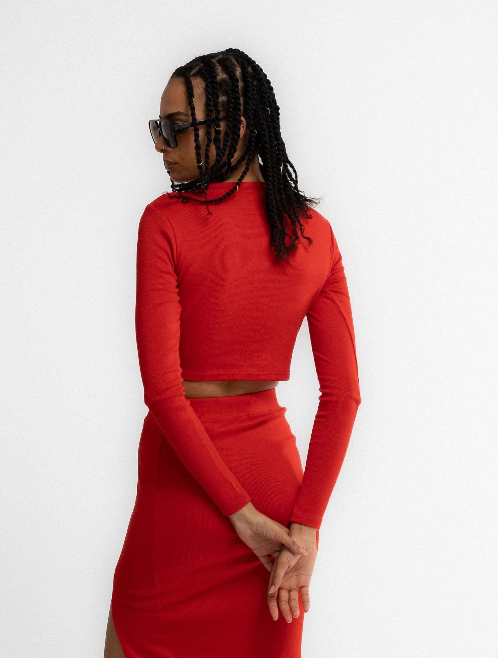 a woman in a cropped top posing with a fiery red long sleeve top from silkroad daughters