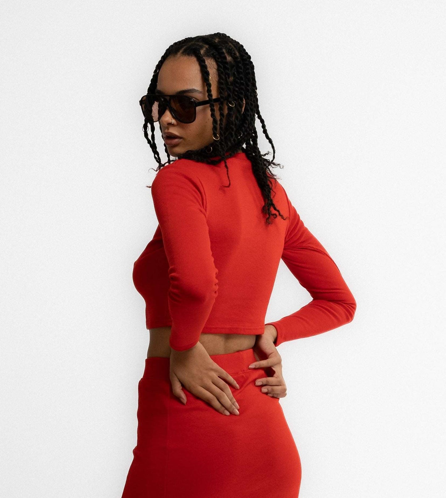 a woman in a cropped top posing with a fiery red long sleeve top from silkroad daughters