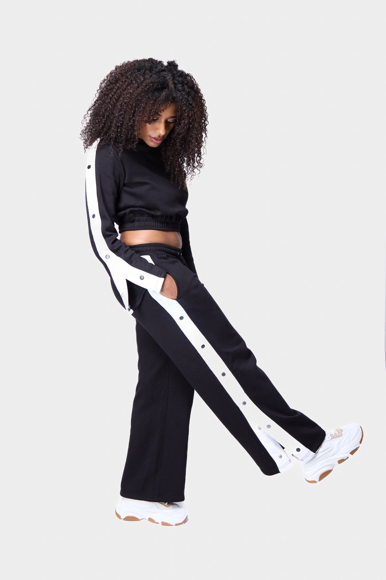Women’s black cropped top with snap-button accents, ideal for sportswear or casual style.