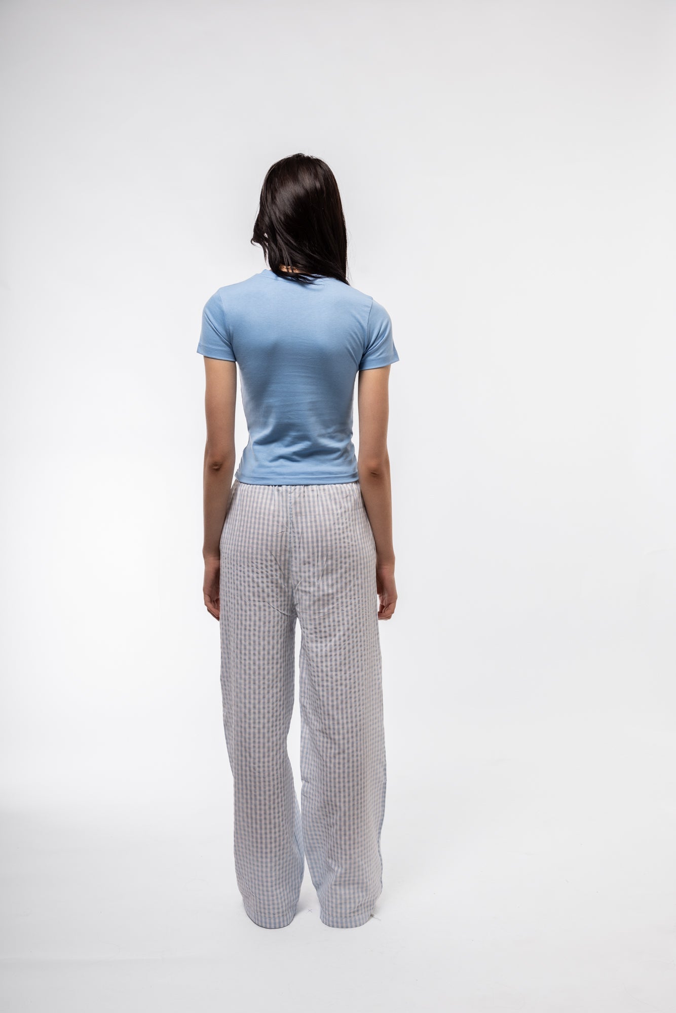 back profile image of model earing the sky blue gingham wide leg trousers