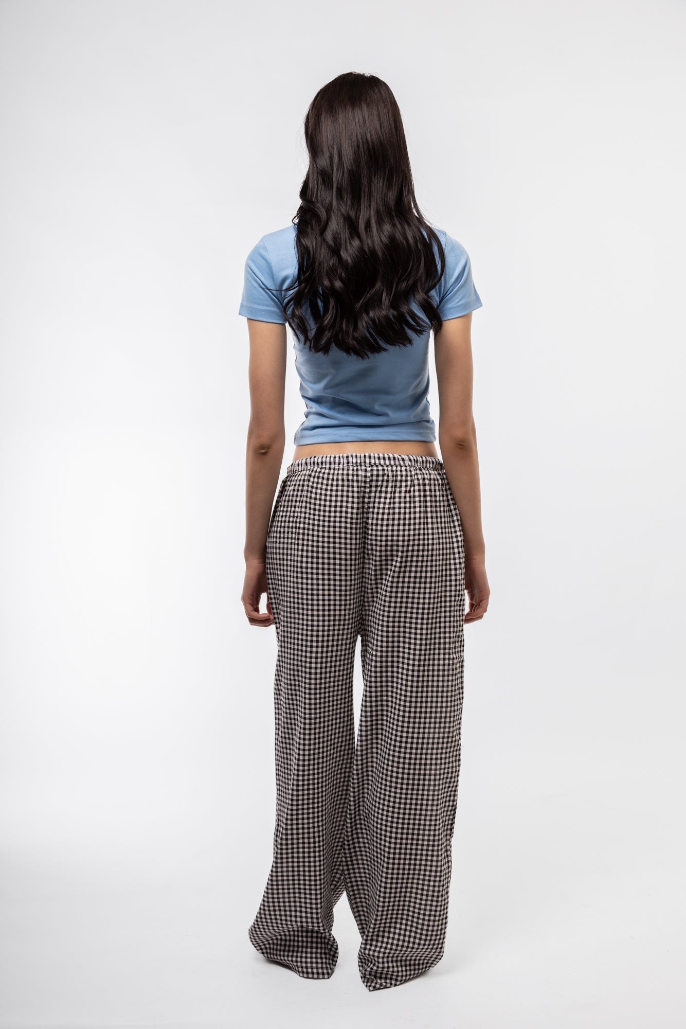 back profile of model wearing the black gingham wide leg trousers