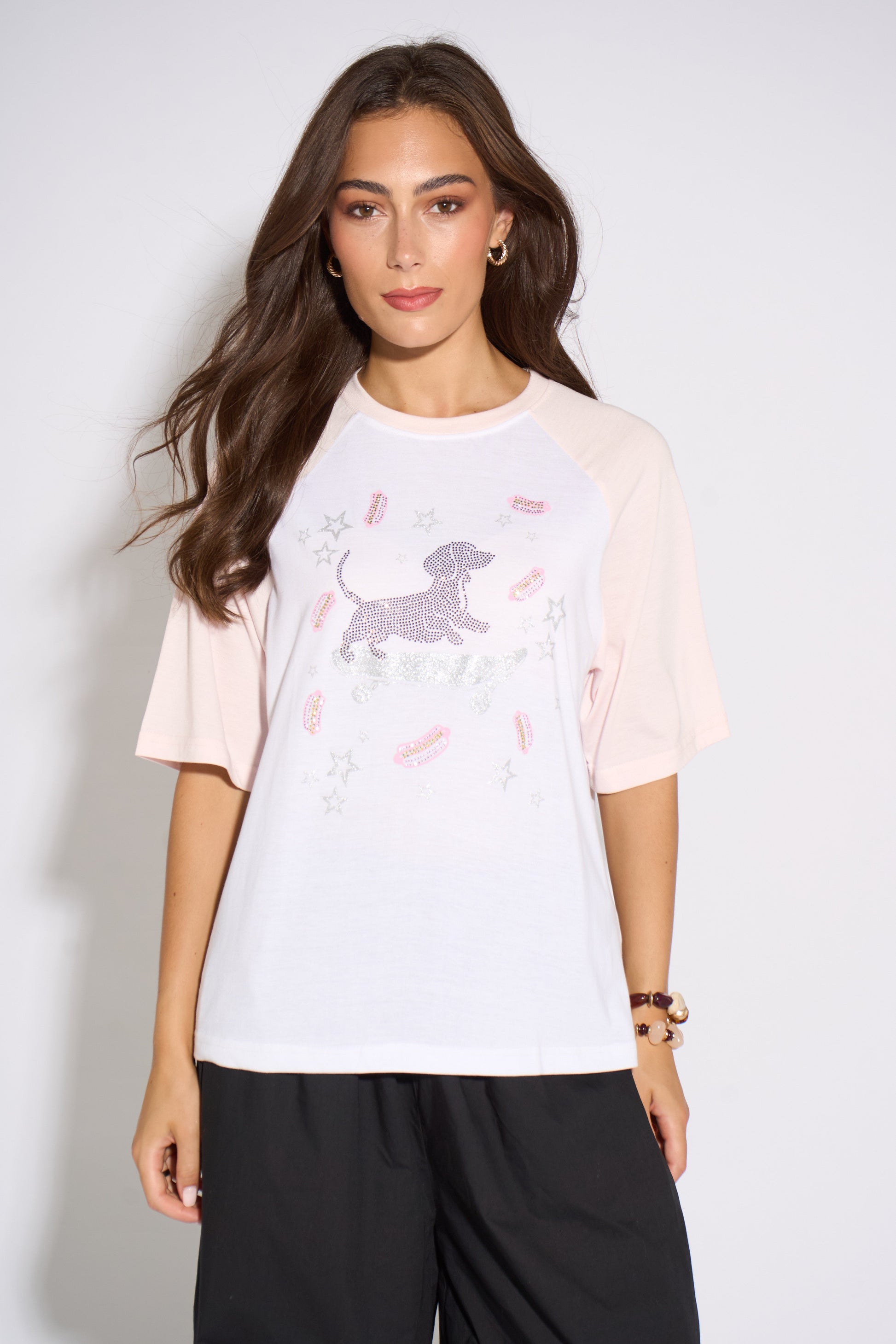 Woman wearing a light pink t-shirt with a graphic design on a plain background