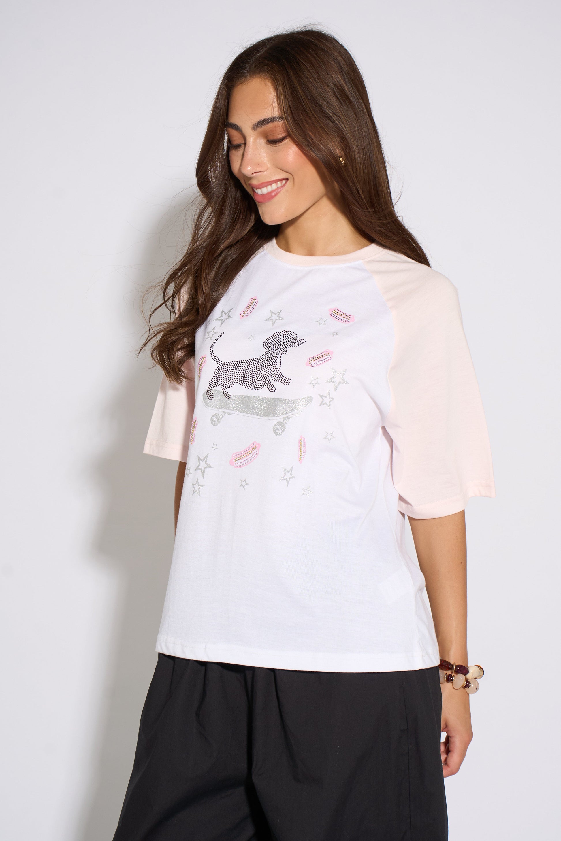 Woman wearing a white t-shirt with a graphic design on a plain background
