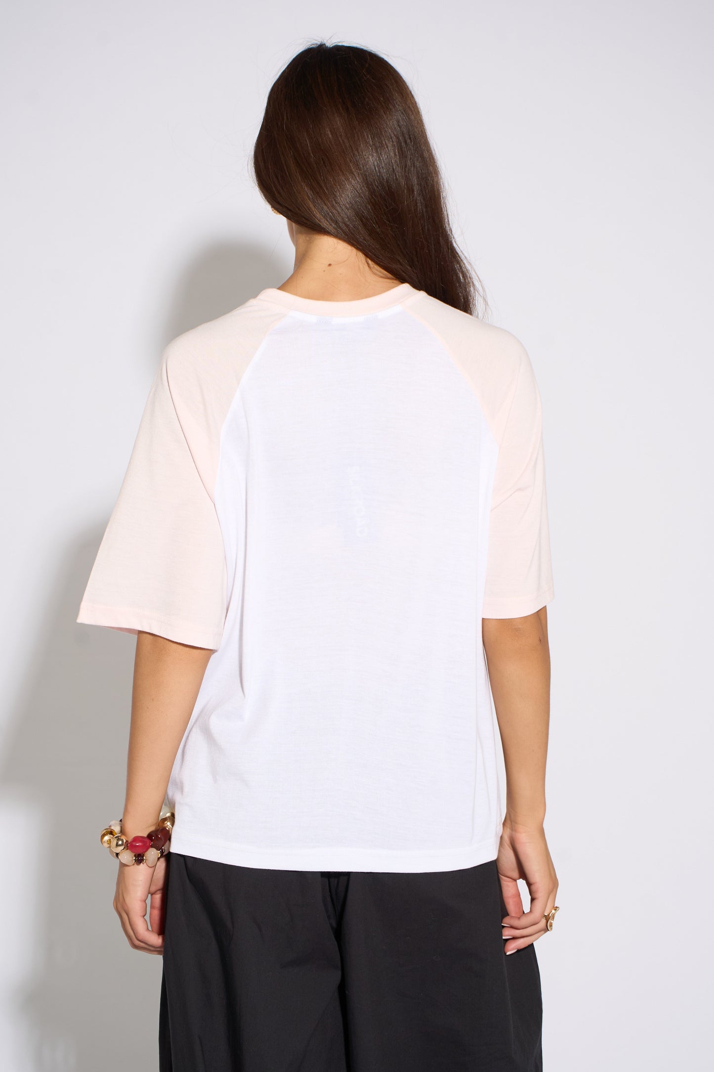 Person wearing a white and pink baseball shirt against a plain background