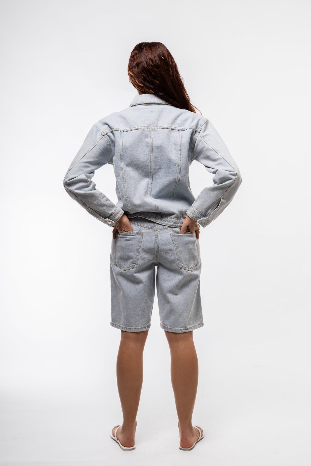 Back view of stud denim jorts featuring studded rear pockets and distressed denim finish.

