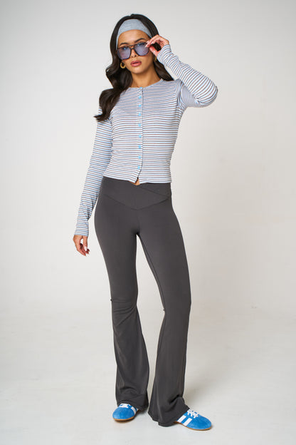 Woman wearing a striped long-sleeve top and gray flared pants on a white background
