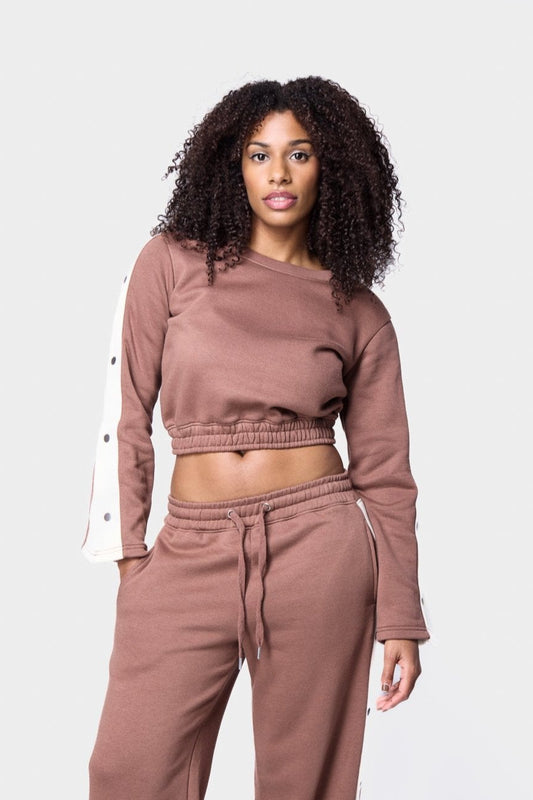 Brown cropped sweater top with white snap buttons on the sleeves for a trendy track suit appearance
