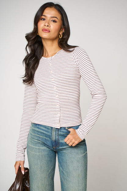 Woman wearing a striped long-sleeve top and jeans against a plain background