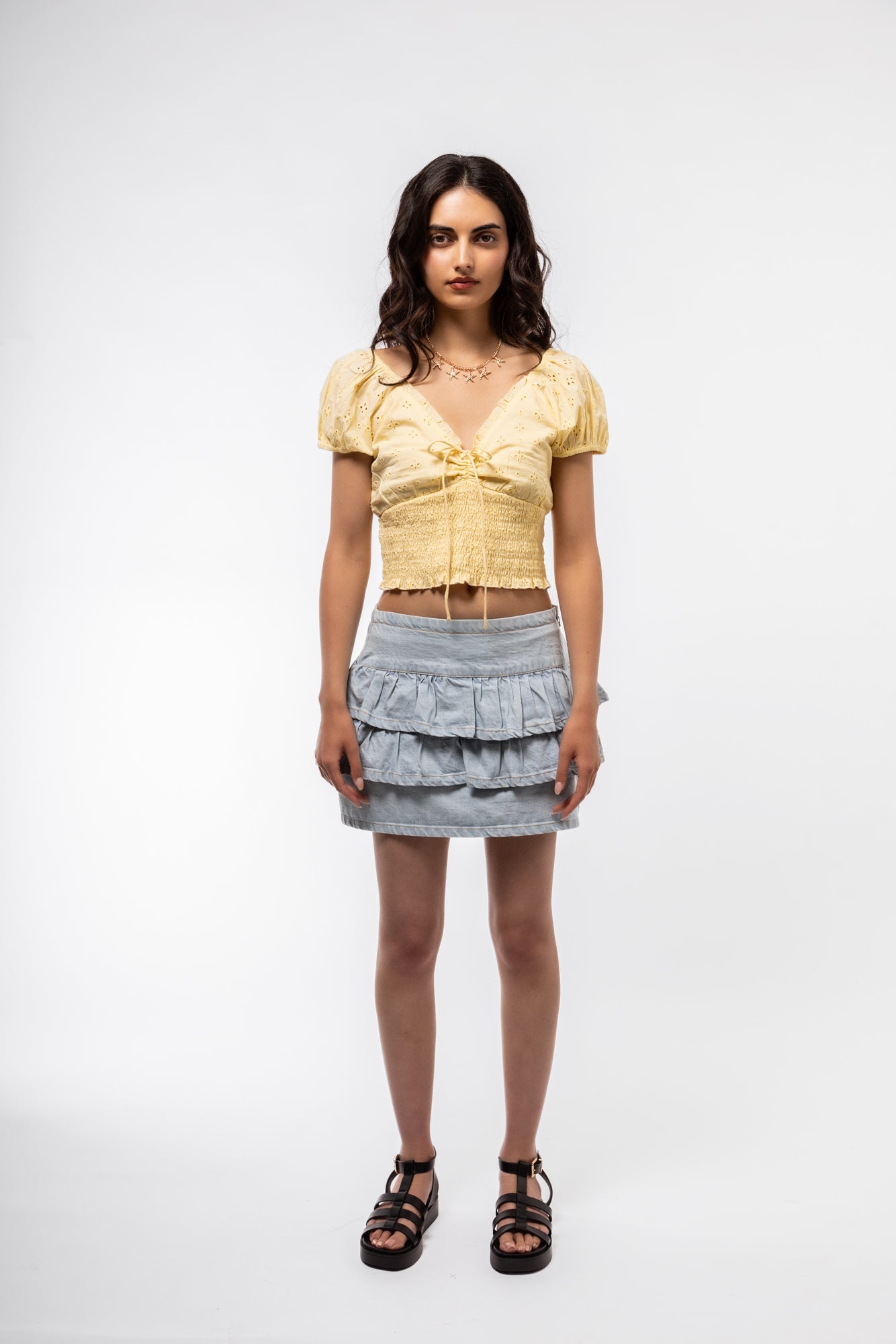 Front profile of ruffled denim wrap skirt with structured waistband and feminine drape.

