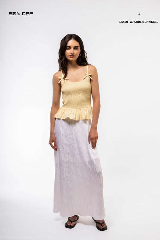 Woman wearing a yellow top and white skirt on a white background with promotional text.