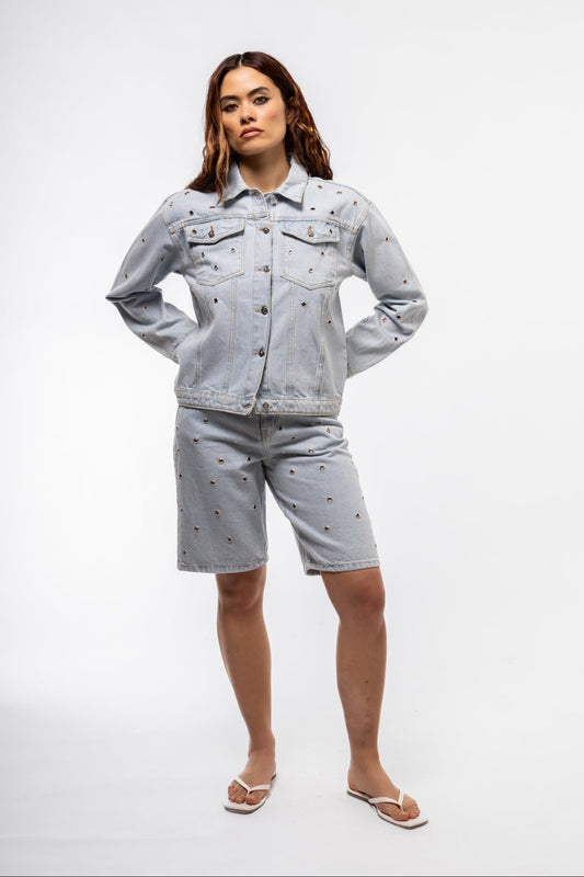 Front view of stud denim jorts with distressed detailing and metal studs on pockets for a bold summer look.

