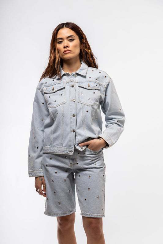Front view of studded denim jacket featuring bold metallic studs and button-front closure

