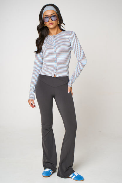 Woman wearing a striped long-sleeve top and gray pants on a white background