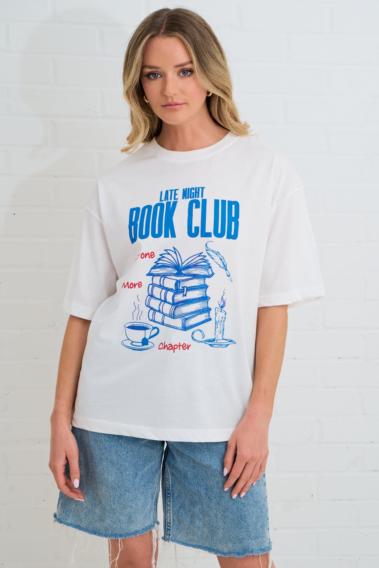 Person wearing a 'Late Night Book Club' t-shirt with book-themed graphics on a white background
