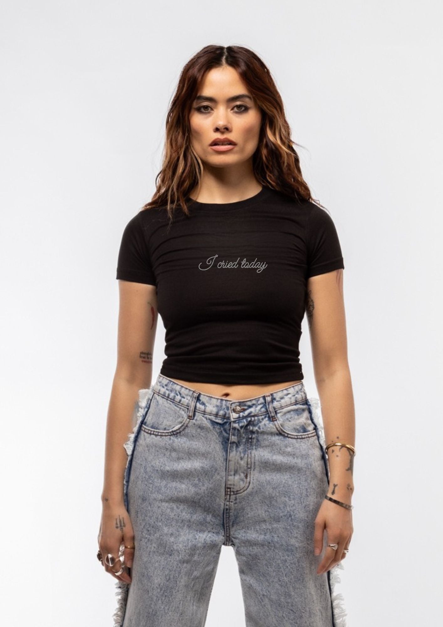 Woman wearing a black t-shirt with text and high-waisted jeans on a white background
