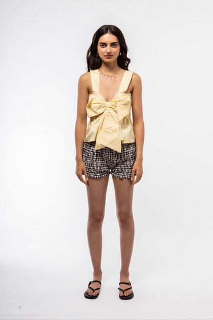 Light yellow cotton cami with bow detail and thin straps, ideal for warm weather.

