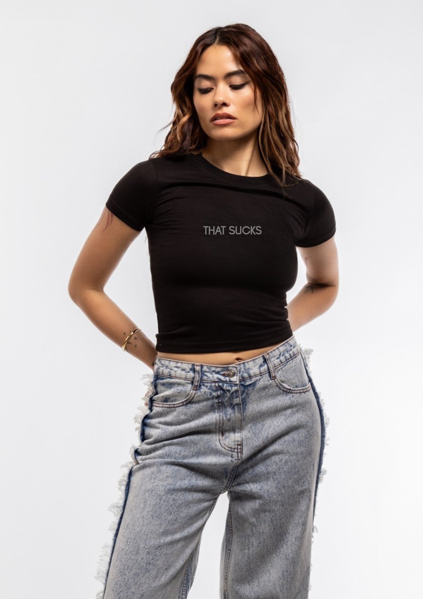 Person wearing a black t-shirt with 'THAT SUCKS' text and light blue jeans on a white background