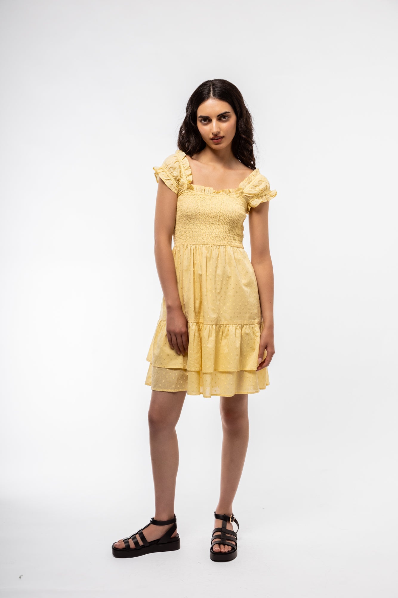 Front-facing image of pastel butter yellow smocked dress with midi-length skirt and soft structure.

