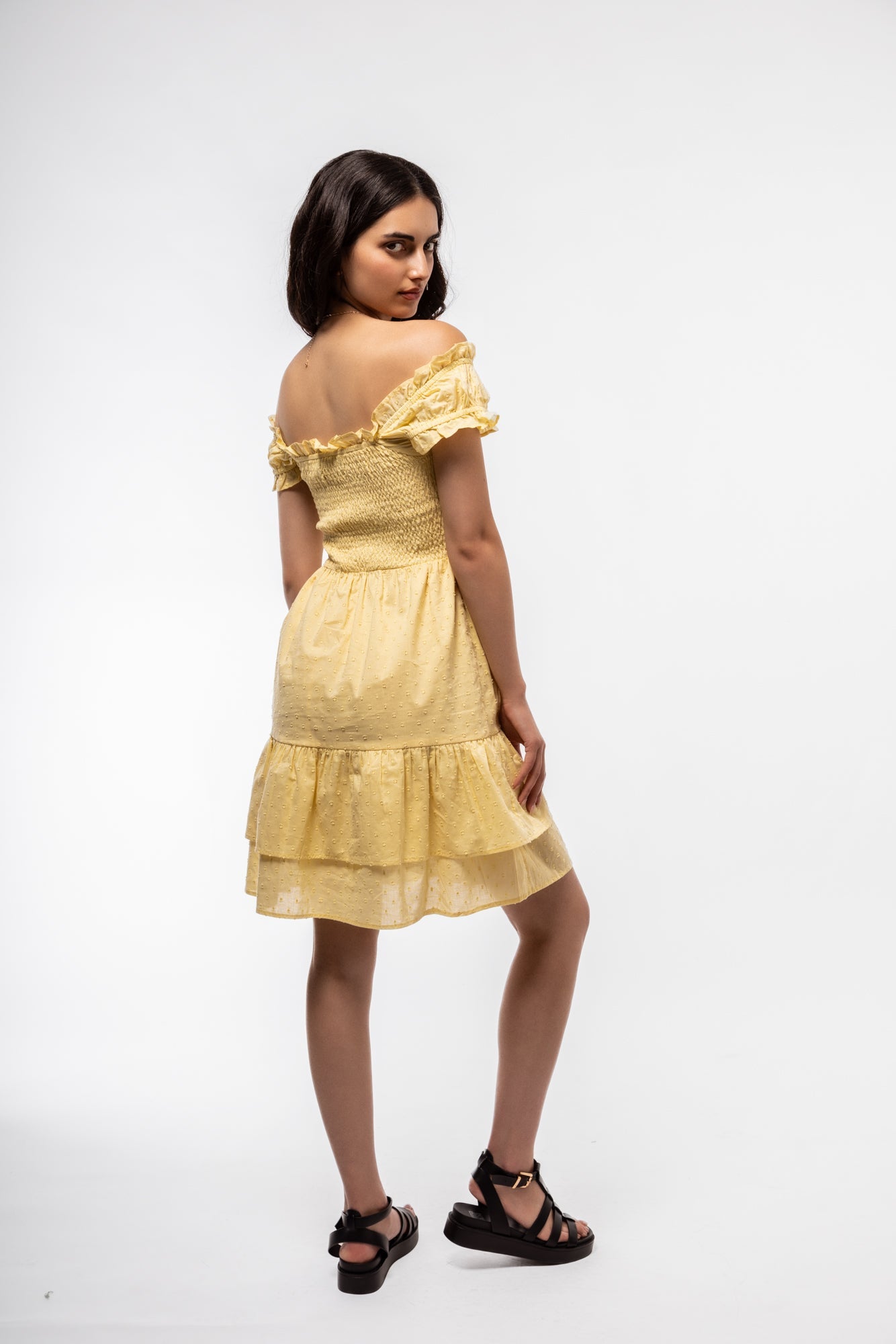 Side-facing shot of summer tea dress in butter yellow with shirred waist and gentle volume.

