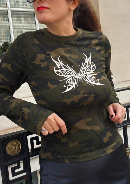 Person wearing a camouflage long-sleeve shirt with a white butterfly design.