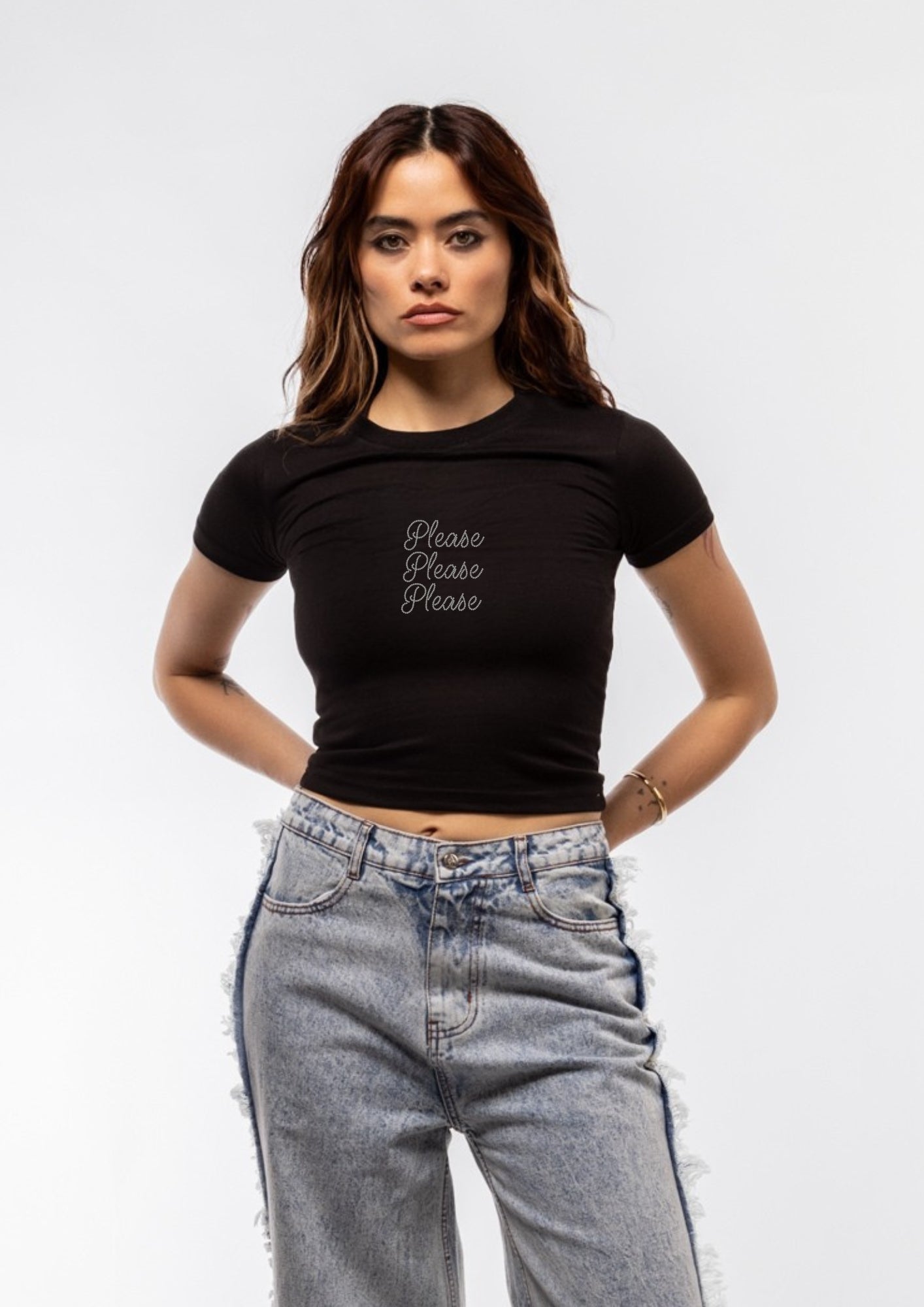 Model  wearing a black t-shirt with 'Please Please Please' text and high-waisted jeans with fringes 