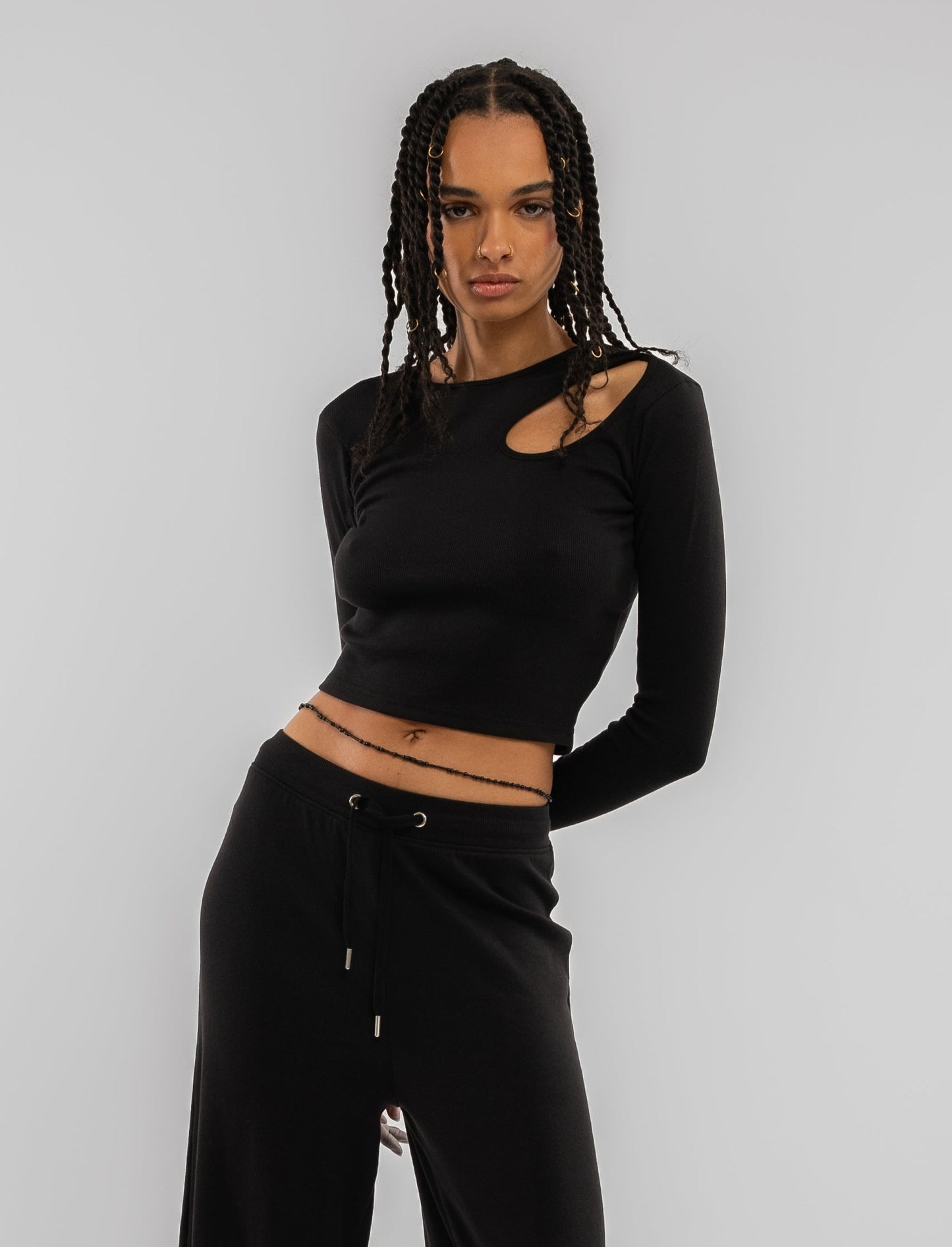 a woman in a black cut out long sleeve rib crop top posing for a picture