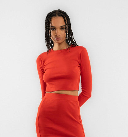 a woman in a cropped top posing with a fiery red long sleeve top from silkroad daughters 