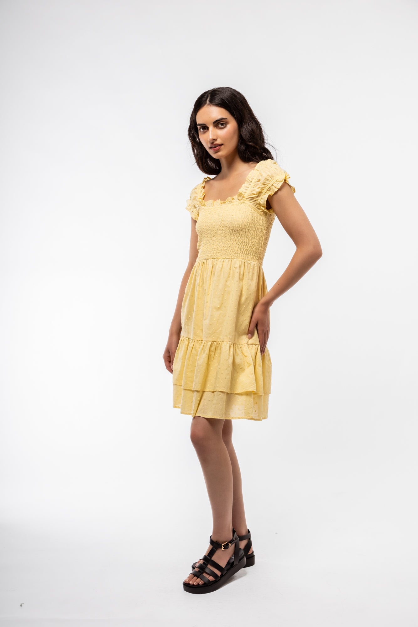 Side-facing shot of summer tea dress in butter yellow with shirred waist and gentle volume.

