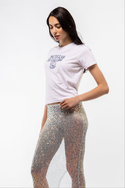 Side profile of The Ocean Is Calling rhinestone tee showing flattering silhouette and partial rhinestone text

