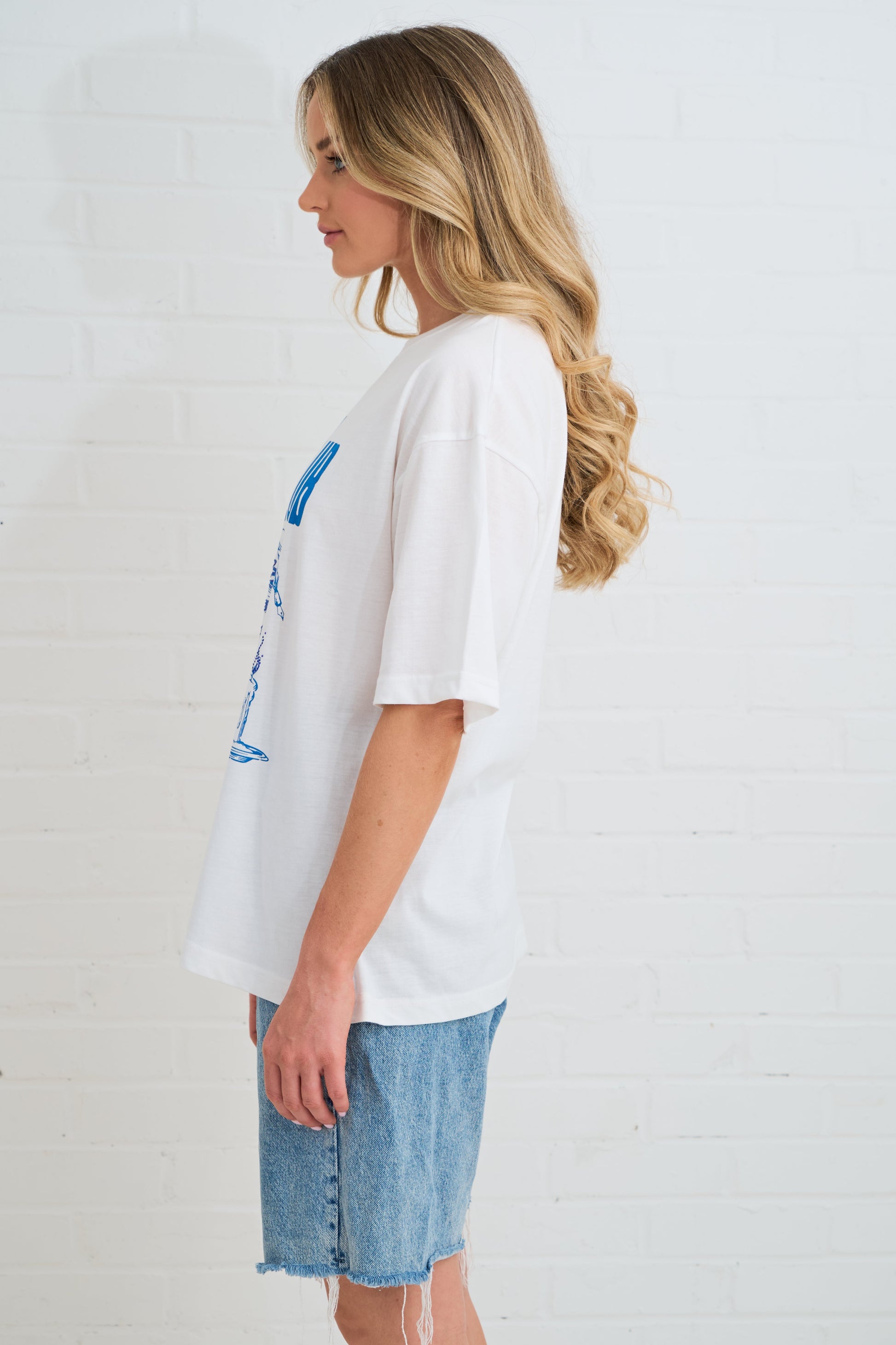 Woman wearing a white t-shirt with a graphic design on a plain background
