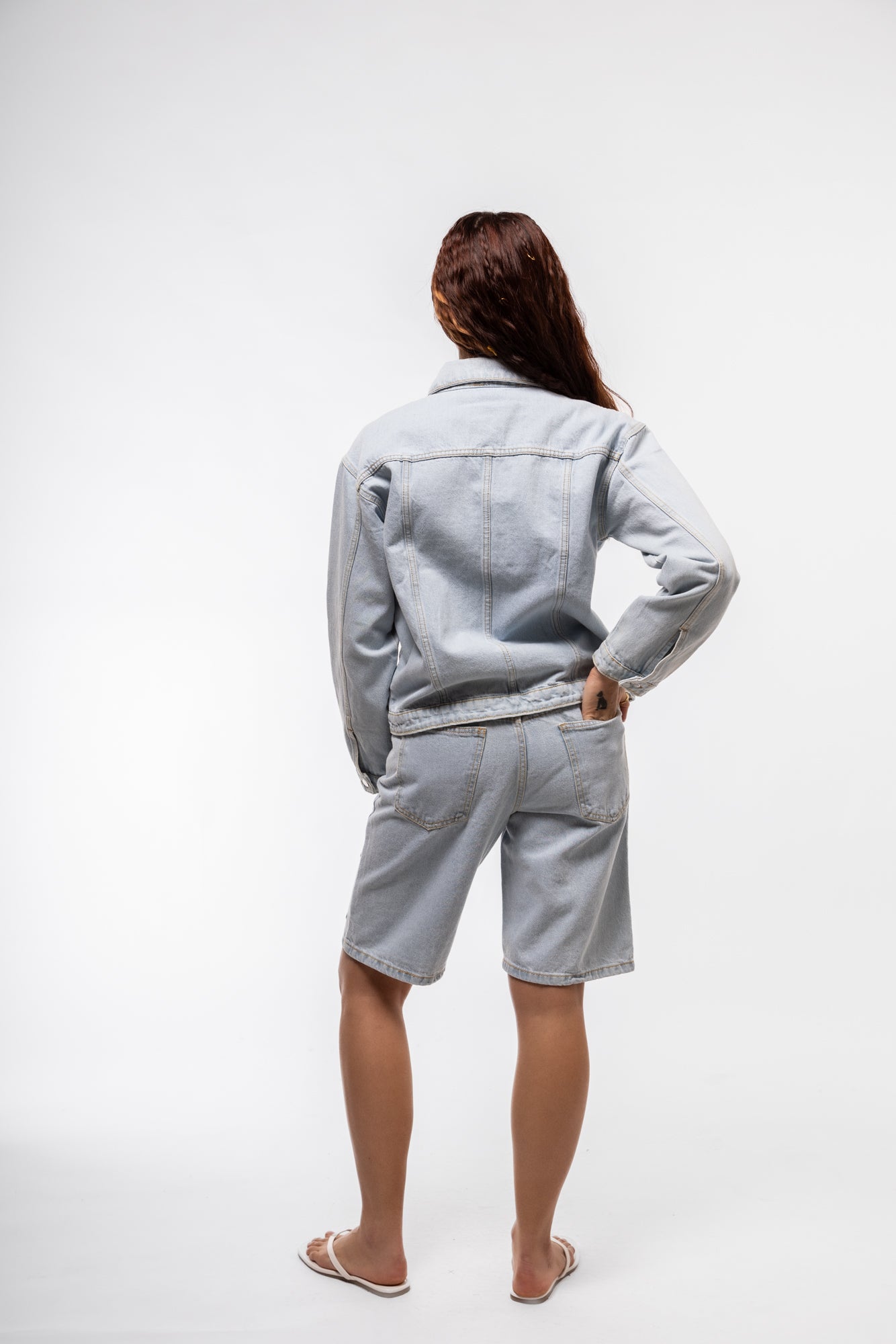 Stud denim jorts rear view with rugged denim texture and silver studs decorating the pockets.

