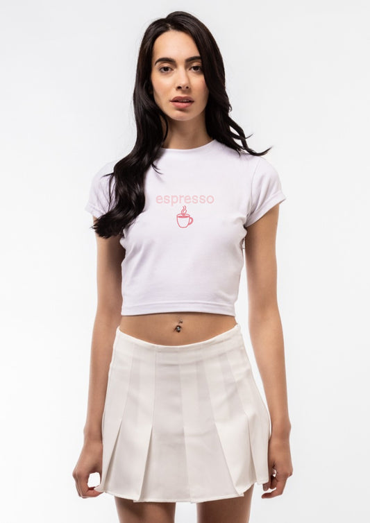 Woman wearing a white t-shirt with a logo and a beige skirt on a white background