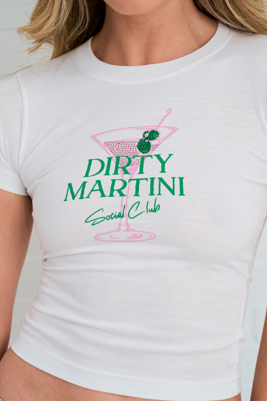 Detail of the  white t-shirt with a graphic with a martini cocktail design with rhinestones  and blue jeans against a white wall