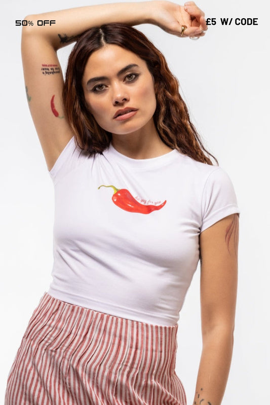 Woman wearing a white t-shirt with a red chili pepper graphic and text, posing against a white background.