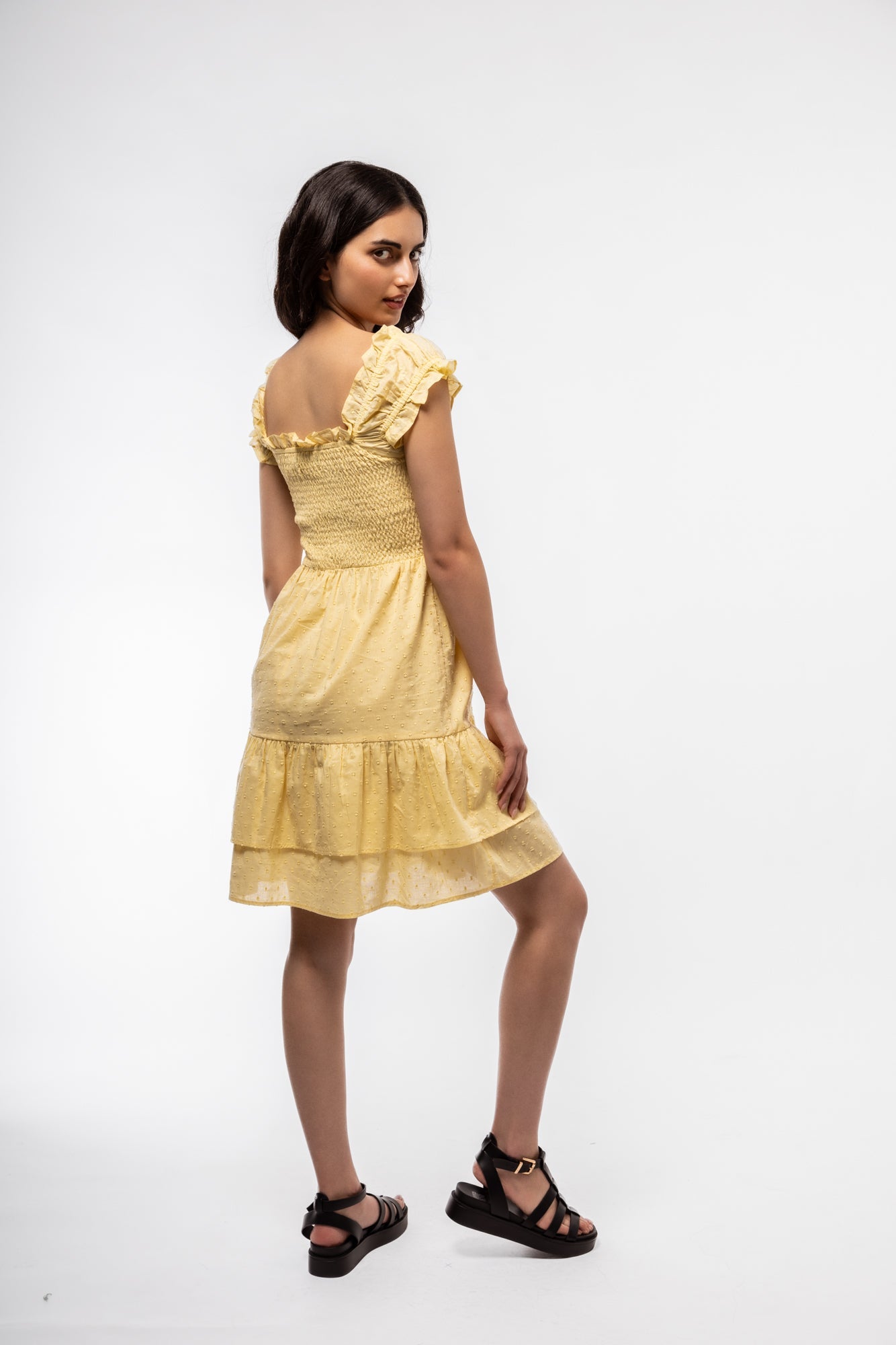 Women’s pastel yellow cotton dress with shirring, shown from the side with breathable texture.


