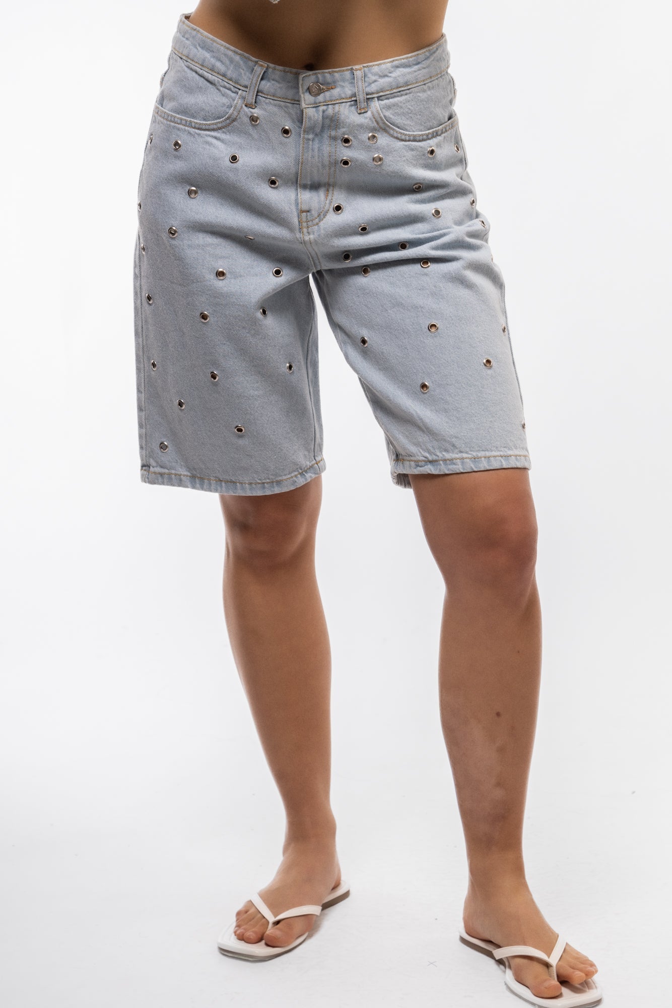 Women’s stud denim jorts front profile highlighting frayed hem and edgy stud embellishments.


