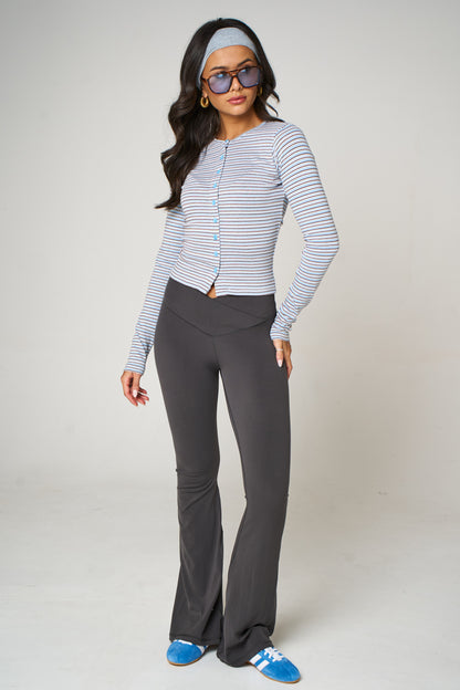 Woman wearing a striped cardigan and gray pants on a white background