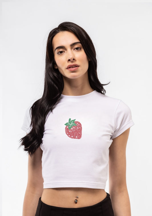 Model  wearing a white crop top with a strawberry graphic on a plain background