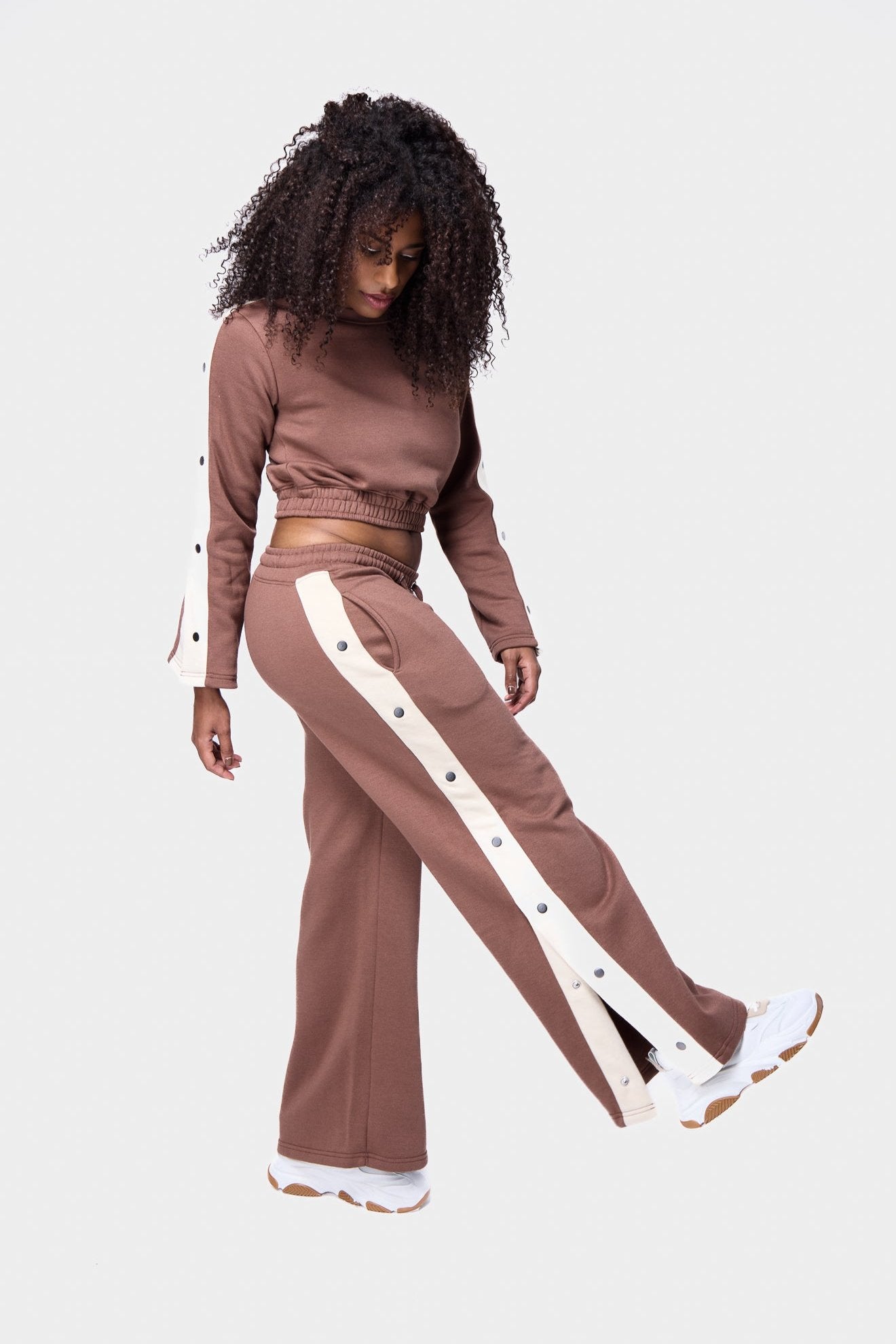 Woman showcasing a raw umber cropped track suit with side snap-button detailing and wide-leg pants.