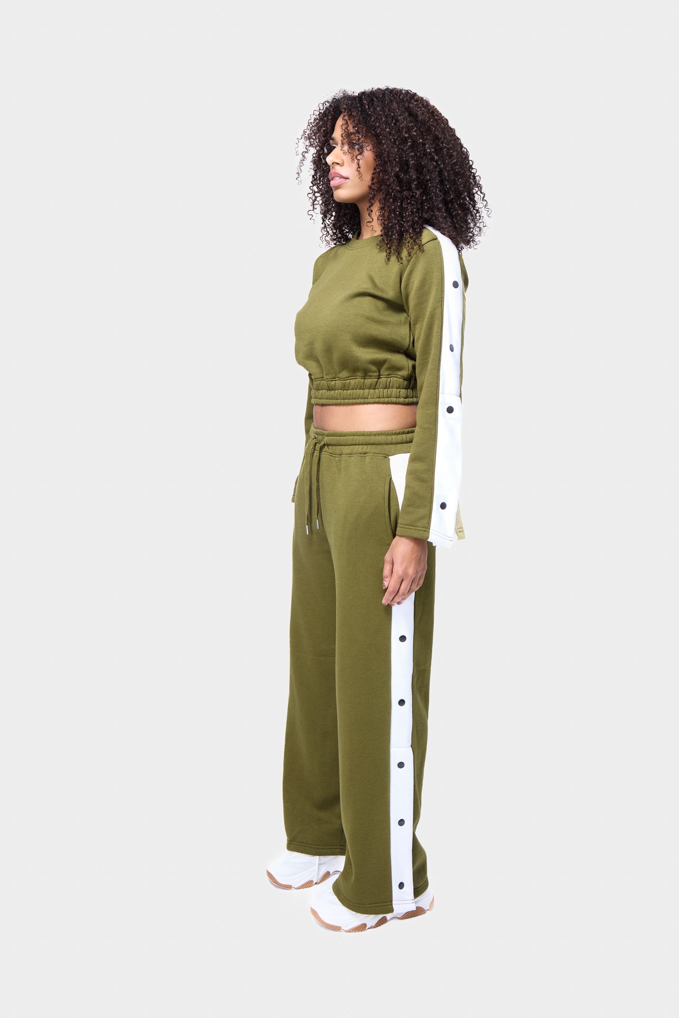 Khaki track suit with snap buttons, featuring a cropped top and wide-leg pants, worn by a woman.